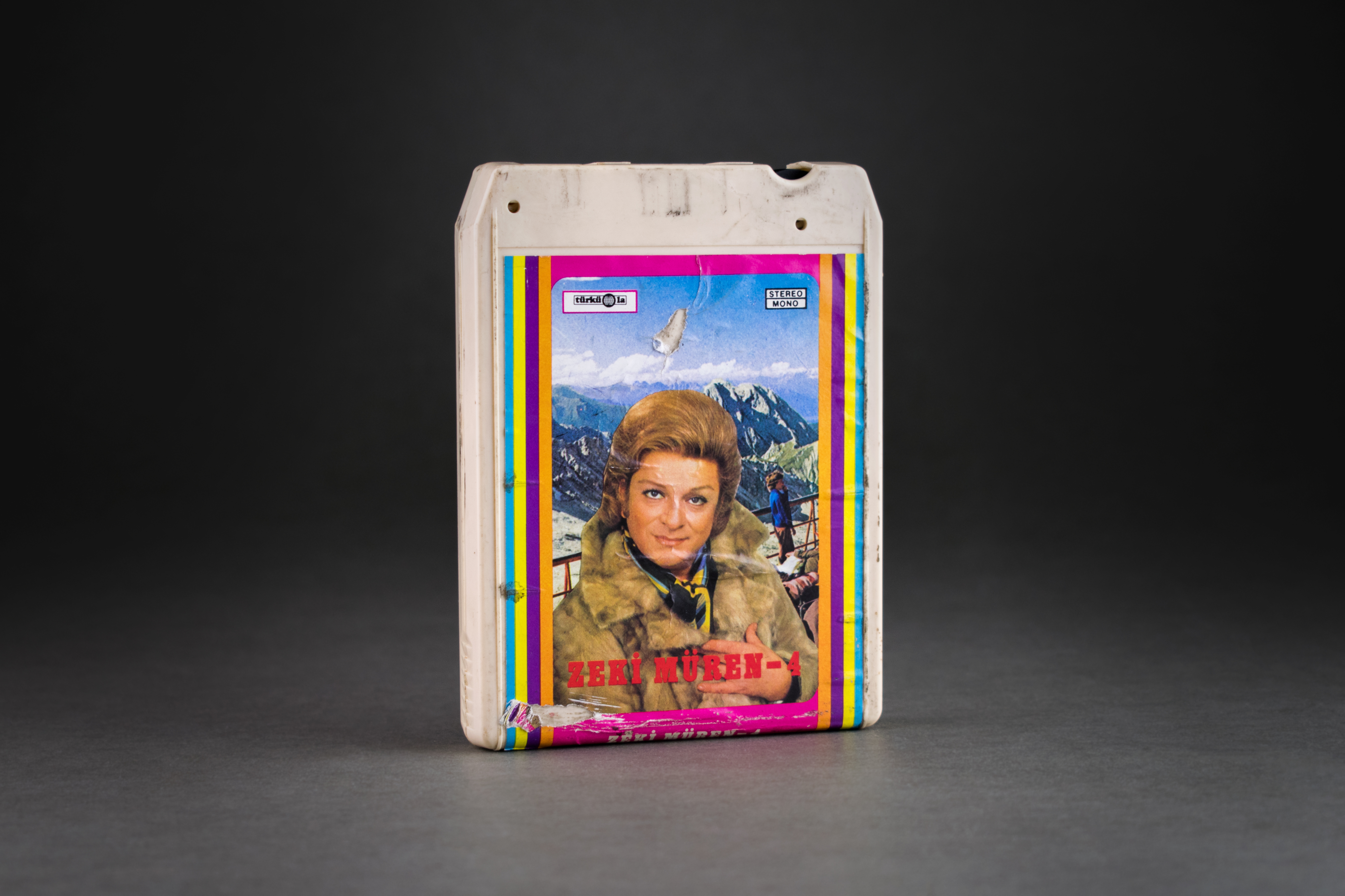 8-track cassette by Zeki Müren, Türküola, 1970. Türküola was the first record company to produce Turkish-language music in Germany. It was founded by Yılmaz Asöcal in Cologne in the 1960s. In addition to LPs, cassettes and later also CDs from well-known Turkish-speaking artists such as Barış Manço, İbrahim Tatlıses or Zeki Müren, from the 1960s, Türküola also contracted numerous migrant workers who had only started a musical career in Germany. This group also included the two best-selling artists from the record label, Metin Türköz and Yüksel Özkasap, who also gained fame in Turkey. In the 1980s, Türküola produced the albums of the well-known musician Cem Karaca. DOMiD Archive, Cologne, BT 0612,0008
