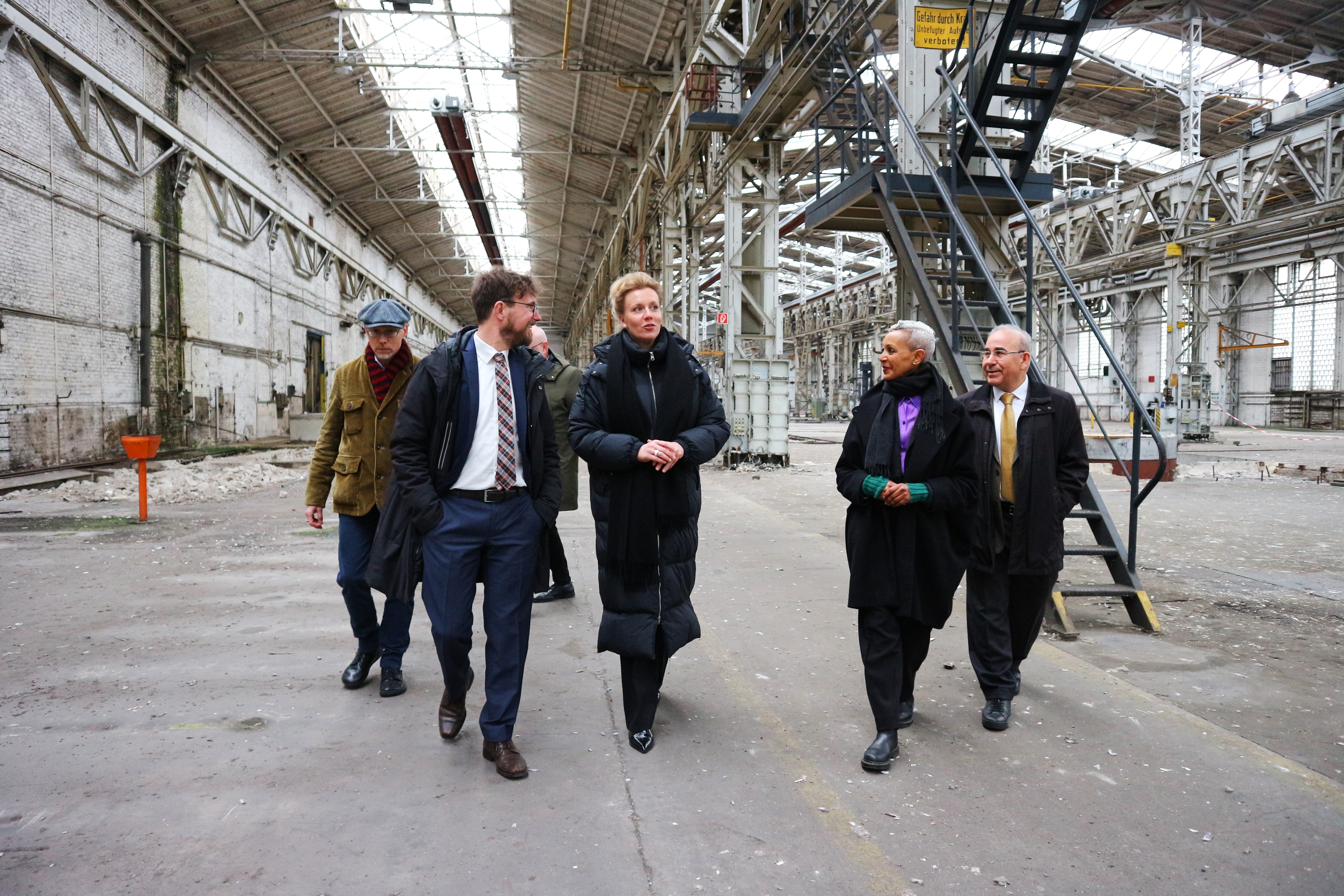 Dr. Robert Fuchs, the Managing Director of DOMiD (front left), and the DOMiD project manager for the museum building ,Yordanos Asghedom (front right), guide the Minister through "Hall 70", where the museum is to be built. Photo: DOMiD archive, Cologne